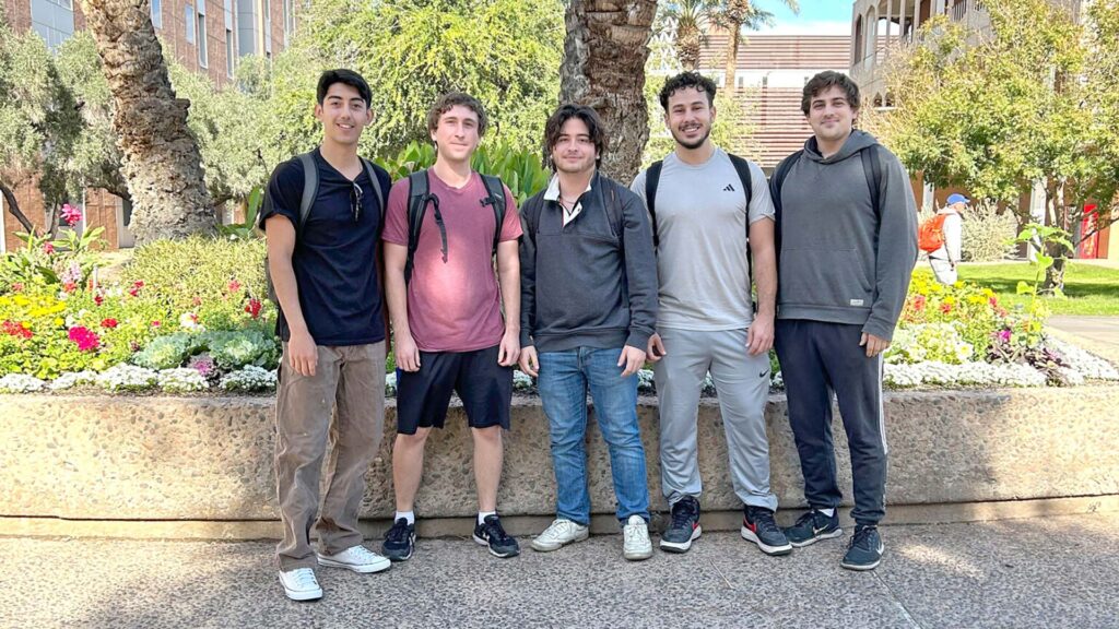 Five students posing outdoors as a team photo