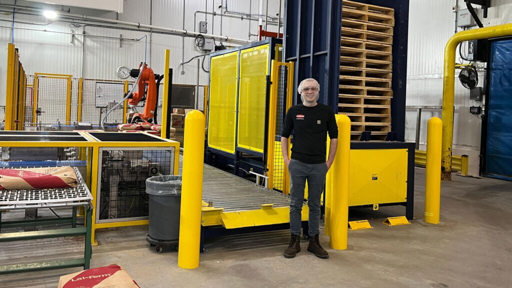 Student posing in front of a robotic arm